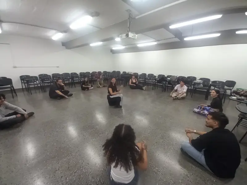 El grupo sentado en círculo en el piso de un salón amplio