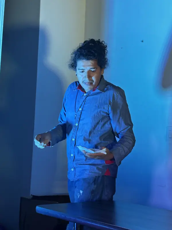 Un actor lee su texto bajo luz azul durante un ensayo