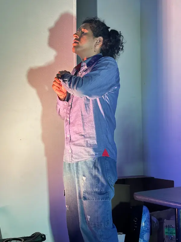 Un actor proyecta su sombra en la pared bajo luz violeta