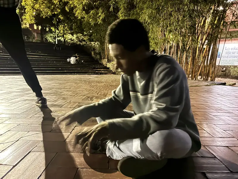 Un integrante arrodillado toca el piso bajo luz cálida