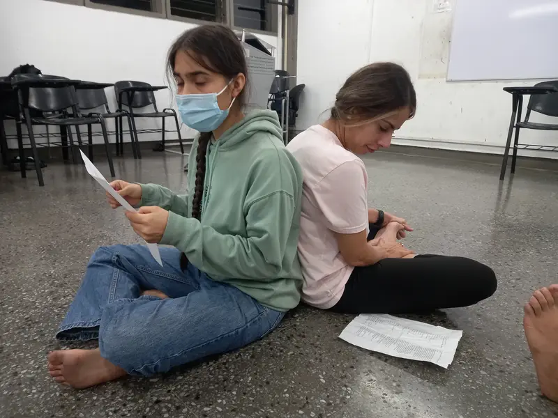 Dos integrantes sentadas en el piso leen sus textos